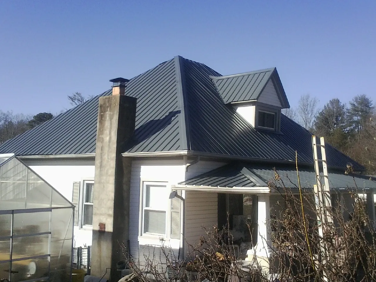 Dark blue standing seam metal roof on a white farmhouse with dormer — Slate & Tile Roof Repair by Roofing Brothers in Ephrata