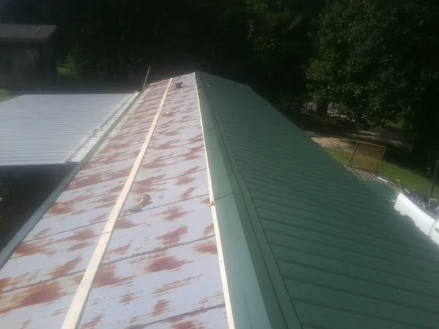 Old rusted panels beside newly installed green metal roofing — Wind Damage Roof Repair by Roofing Brothers in Ephrata