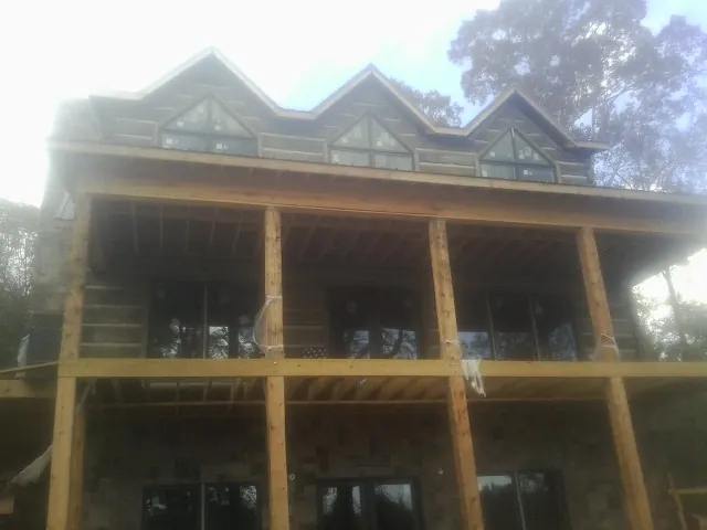Dormers and porch framing on a large log home under construction — Roof Coating work by our crew in Ephrata